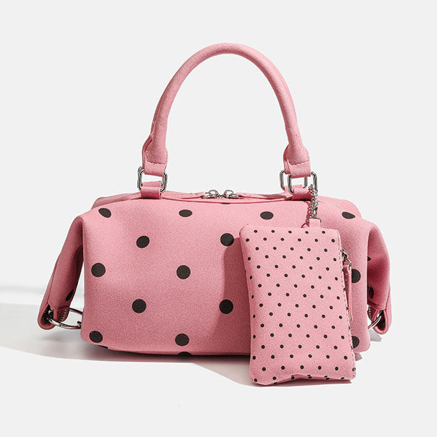 Pink handbag with black polka dots and matching pouch on a light gray background