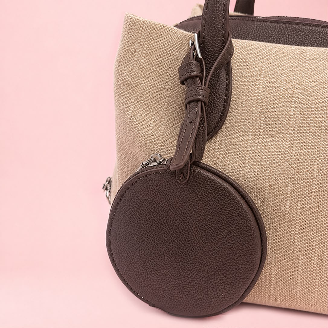 Close-up of detachable round coin pouch charm on linen tote bag